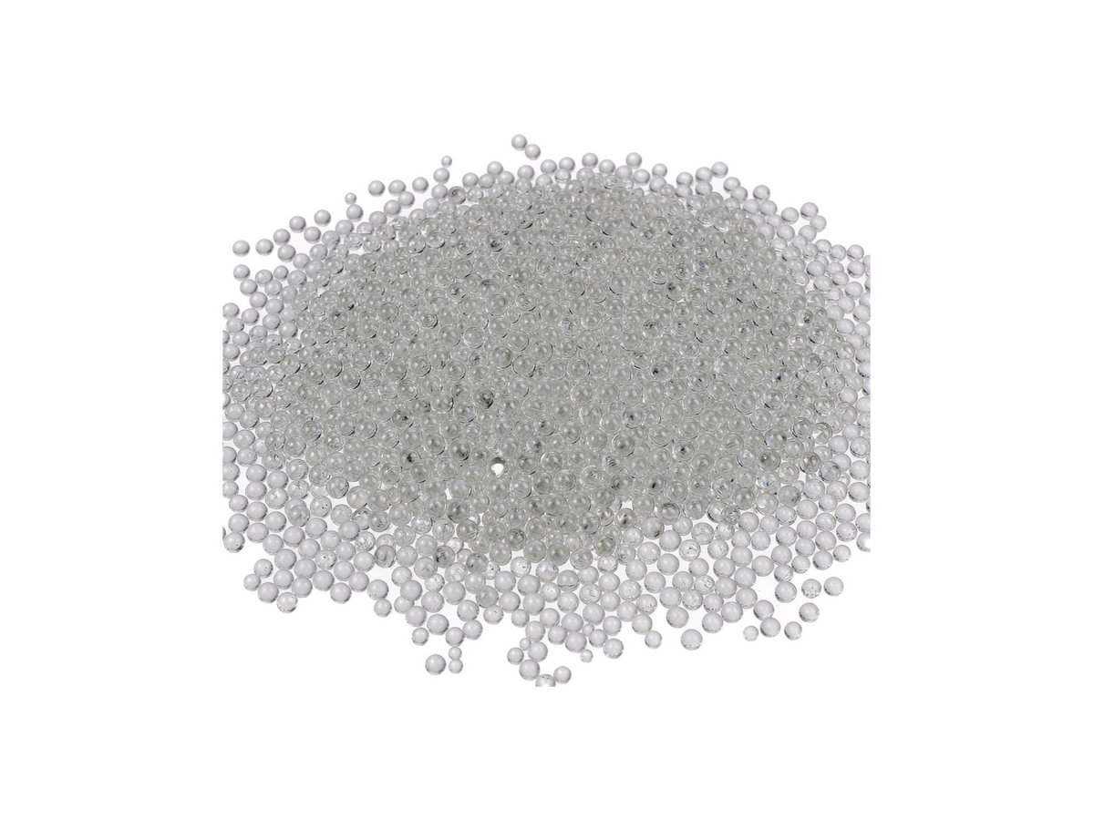Fine round transparent glass beads for shot peening and blasting, spread on a white surface